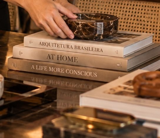 Pilha de livros de arquitetura e uma bandeja de mármore sobre a mesa